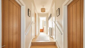 A wooden staircase leading to a room with a view, framed pictures on the walls, and a ceiling light. - Host Stay Stille House (Chathill)