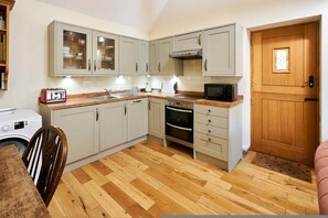 A compact kitchen with a washing machine, a microwave, and a toaster. - Host Stay The Tiled Cottage (Ashford)
