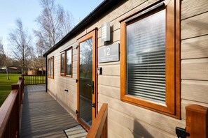 A wooden exterior with a number '12' sign, a glass door, and a deck. - Host Stay Molly s Place (Morpeth)
