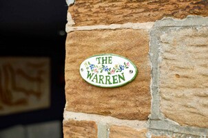 Un muro de ladrillo con un letrero que dice 'THE WARREN'.