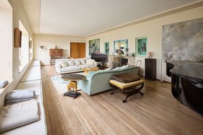 A living room with a sofa, a television, a fireplace, and artwork on the walls. - Host Stay Joldwynds (Dorking)