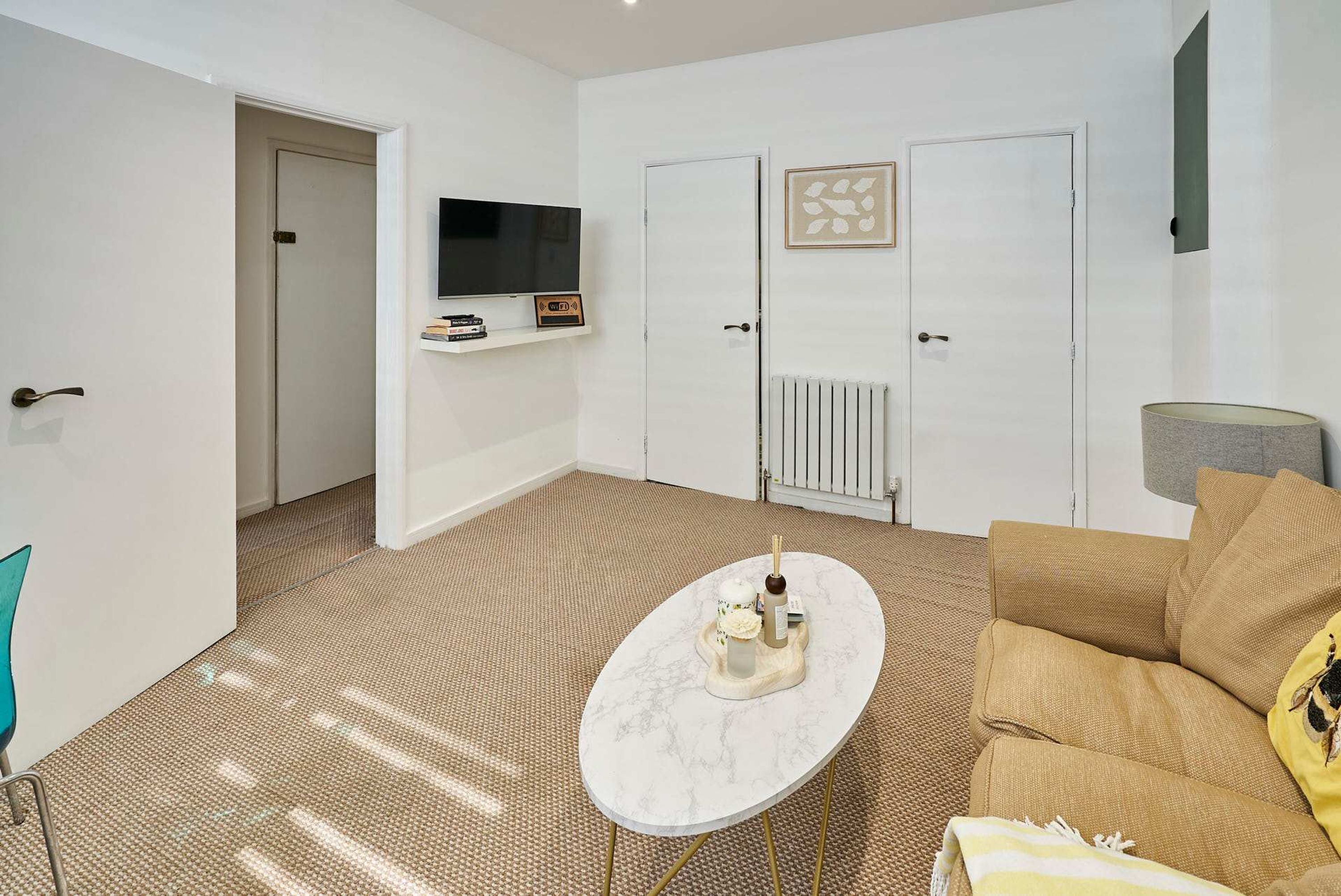 A room with a sofa, a coffee table, a TV, a radiator, and a door.