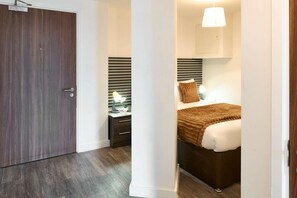 Ein Schlafzimmer mit Bett, Nachttisch, Lampe und einer Pendelleuchte.