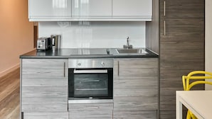 A modern kitchen with grey cabinetry, a built-in oven, a sink, and a toaster.