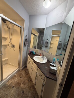 Une salle de bain avec une douche à l’italienne, un lavabo et un miroir.