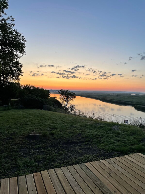 A wooden deck overlooking a calm body of water with a sunset sky.
