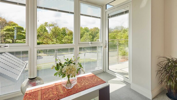 A room with large windows, a table with a vase of flowers, and a potted plant. - Host Stay Apartment 8 (Scarborough)