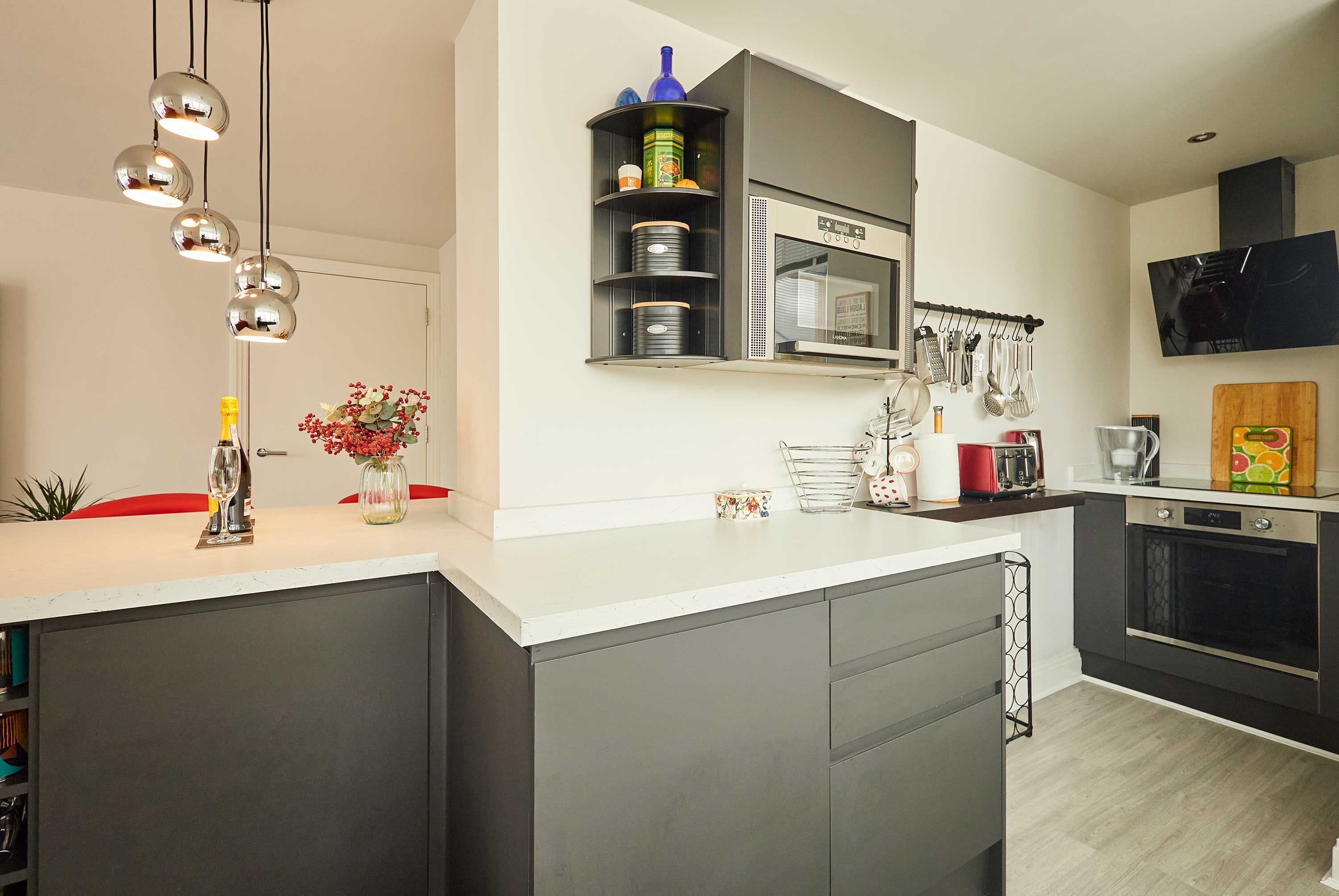 Une cuisine moderne dotée d’un îlot central, d’appareils électroménagers intégrés et d  ’un luminaire suspendu.