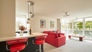 A modern kitchen with a red bar stool, a red sofa, and a large window. - Host Stay Apartment 8 (Scarborough)