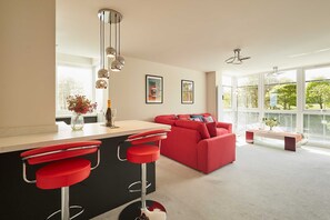 A modern kitchen with a red bar stool, a red sofa, and a large window. - Host Stay Apartment 8 (Scarborough)