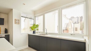 A modern kitchen with a large window, dark cabinetry, and a potted plant. - Host Stay Apartment 8 (Scarborough)