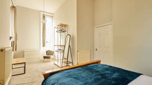 A bedroom with a bed, a radiator, a chair, a coat rack, and a door. - Host Stay Flat 2 Club Chambers (Malvern)