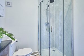 A bathroom with a glass-enclosed shower, a toilet, and a sink with a plant. - Host Stay Flat 2 Club Chambers (Malvern)