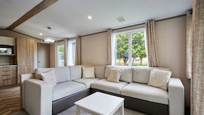 Una sala de estar moderna con un sofá modular, una mesita blanca y una zona de cocina con microondas.