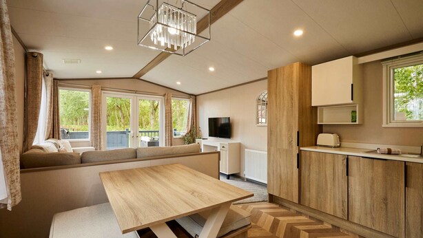 Un espacio habitable compacto con sofá, mesa de comedor, televisor y zona de cocina.