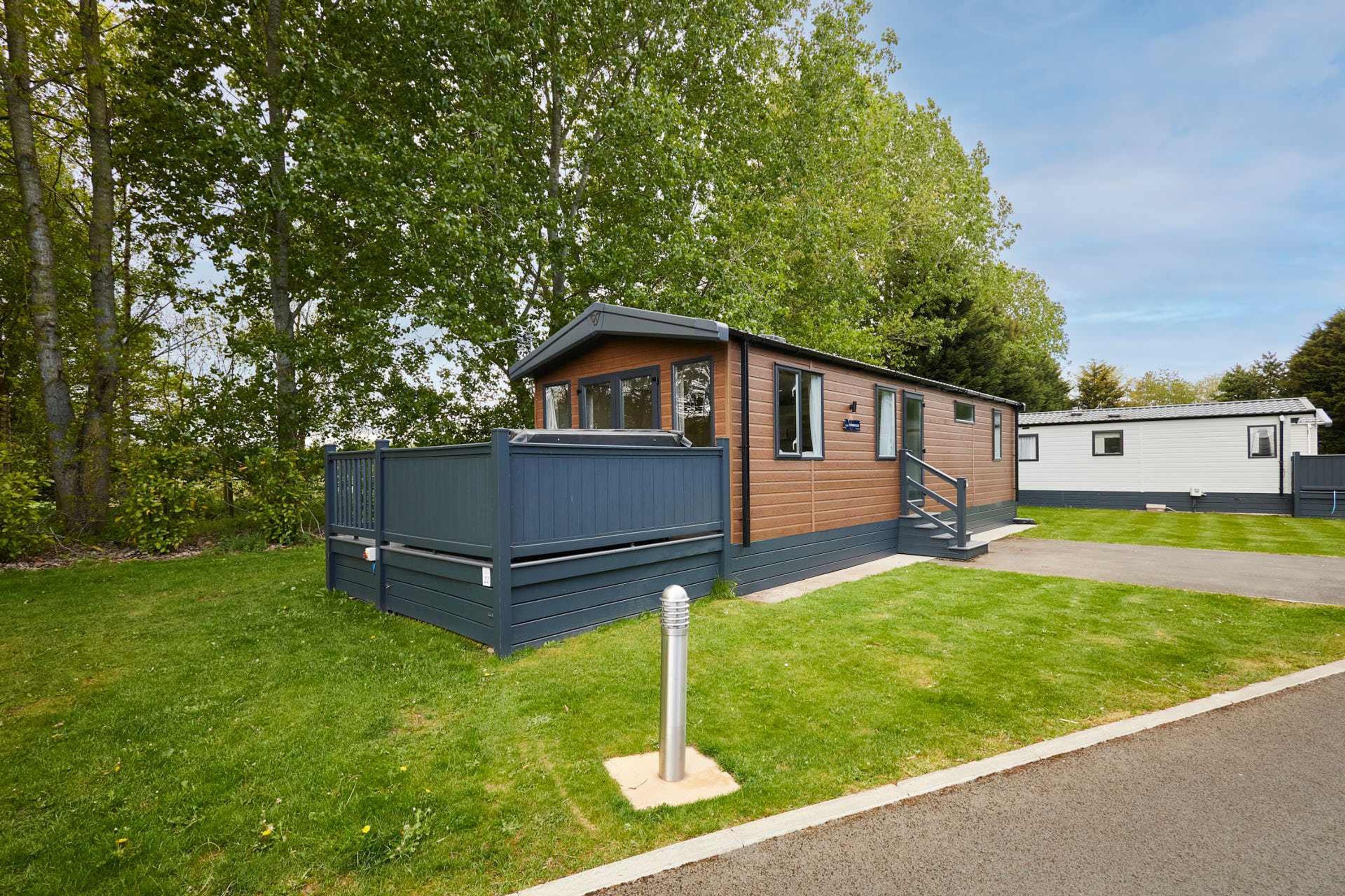 A mobile home with a deck, a small staircase, and a paved driveway.