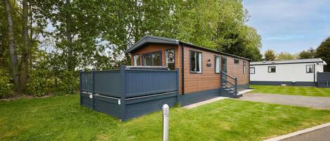 A mobile home with a deck, a small staircase, and a paved driveway.
