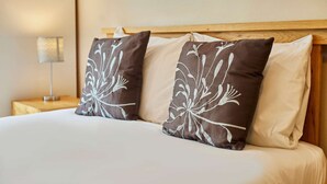 A bed with white bedding and two decorative pillows with a floral pattern.