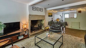 Una sala de estar con chimenea, televisor y zona de estar.