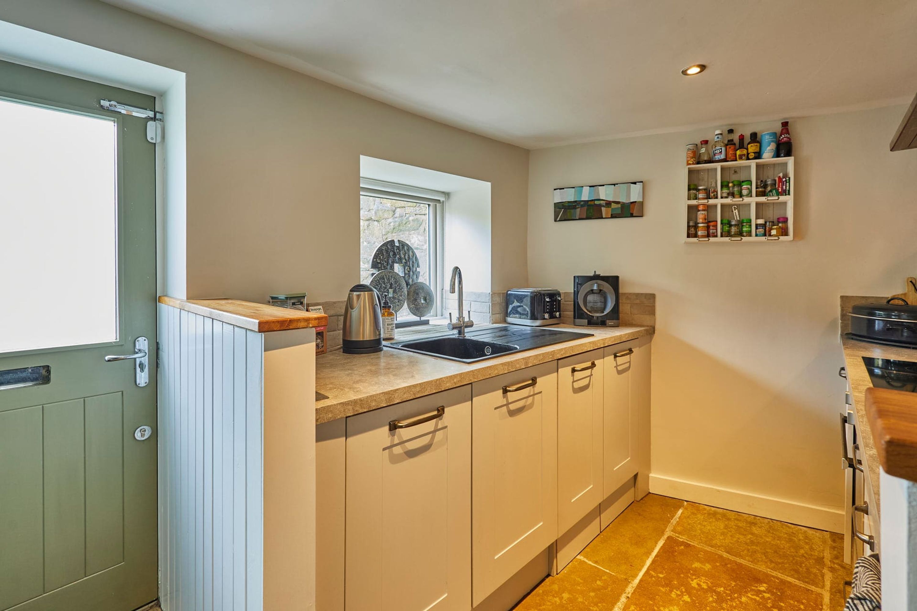 A compact kitchen with a sink, stove, and countertop storage.