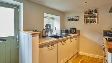 A compact kitchen with a sink, stove, and countertop storage.