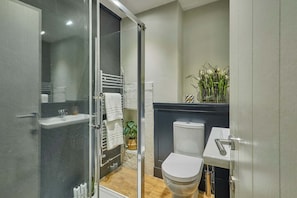 A modern bathroom with a glass shower enclosure, a toilet, a sink, and a small plant on the counter. - Host Stay Lower Cross Lee Cottage (Todmorden)