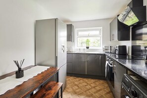 Eine moderne Küche mit grauen Schränken, einer Holzbank, einem Spülbecken und einem Fenster mit Pflanze.