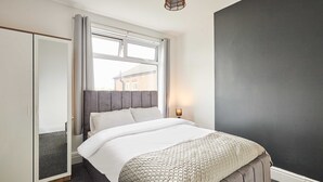 Una camera da letto con un letto, un armadio, una finestra con tende e un muro con finitura testurizzata.