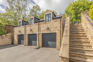 A stone building with two garage doors, a staircase, and a small outdoor area. - Host Stay Woolands View (Keighley)
