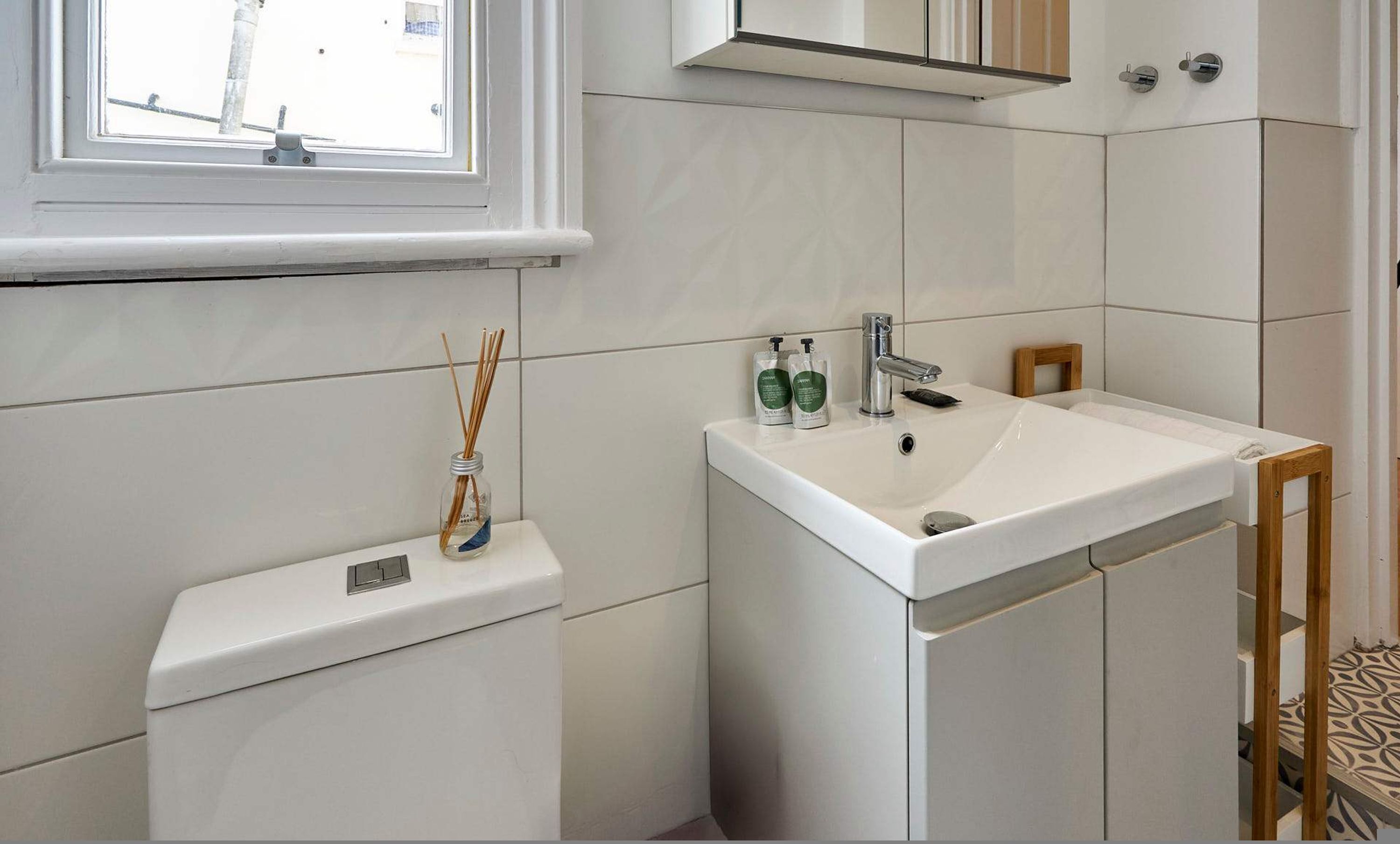 A bathroom with a toilet, sink, and window.