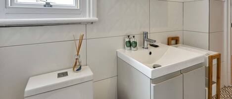 A bathroom with a toilet, sink, and window.