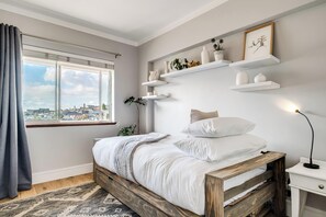 Ein Schlafzimmer mit einem Bett, einem Nachttisch, einem Fenster mit Vorhängen und Wandschränken mit Dekoration.