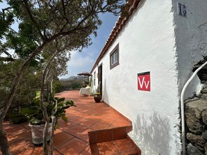 A white building with a red and white sign, terracotta tiled flooring, and a potted plant. - TH - Casa Yerbabuena (Villa de Mazo)