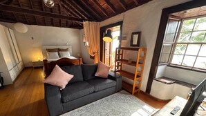 Una habitación con sofá, cama, escritorio y ventana.
