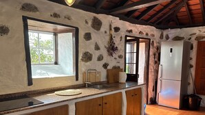 Una cocina con pared de piedra, armarios de madera, un refrigerador Bosch y una ventana con vistas.