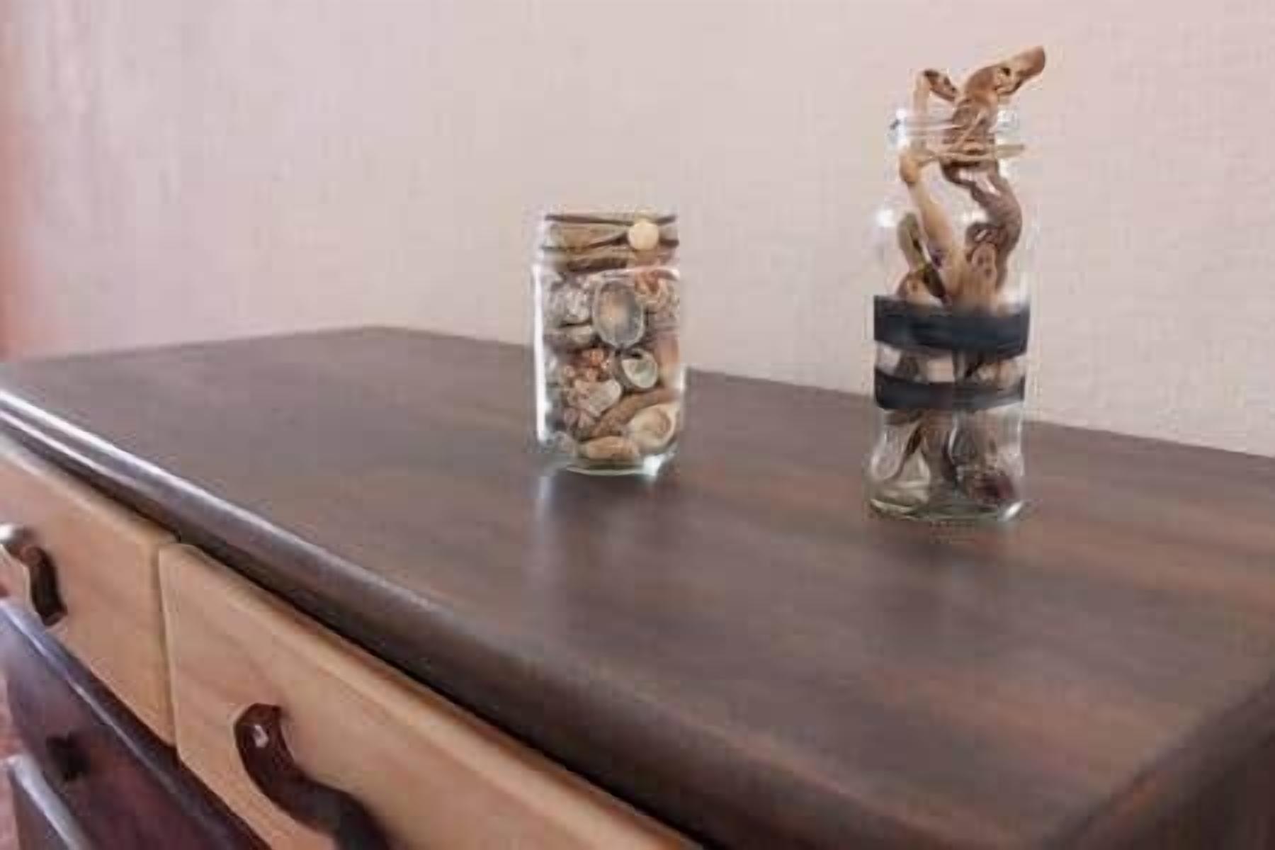 Two glass jars with decorative items on a dark wooden table.