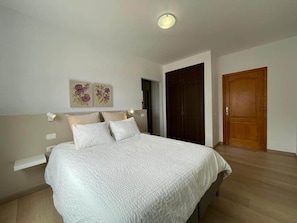 A bedroom with a bed, a nightstand, a wall-mounted light, a door, and a wall decoration. - TH - Mirador de Cristina (Breña Alta)