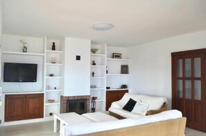 A living room with a flat-screen TV, white shelving, a fireplace, and a wooden door. - TH - Mirador de Cristina (Breña Alta)
