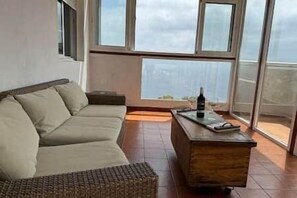 A room with a sofa, a small table, and large windows. - TH - Mirador de Cristina (Breña Alta)