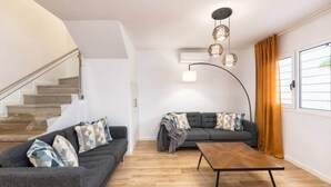 Un soggiorno moderno con una scala, due divani, un tavolino da caffè e una lampada a sospensione.