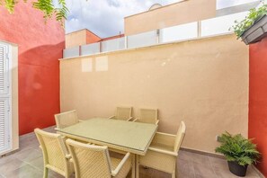 A patio with a table and chairs, a potted plant, and a red wall. - Tendal Duplex - By Tendal Hosting (Santa Cruz de La Palma)