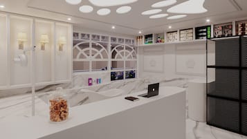 A modern bathroom with a marble countertop, a glass jar of snacks, a laptop, and a shower area with a glass door.