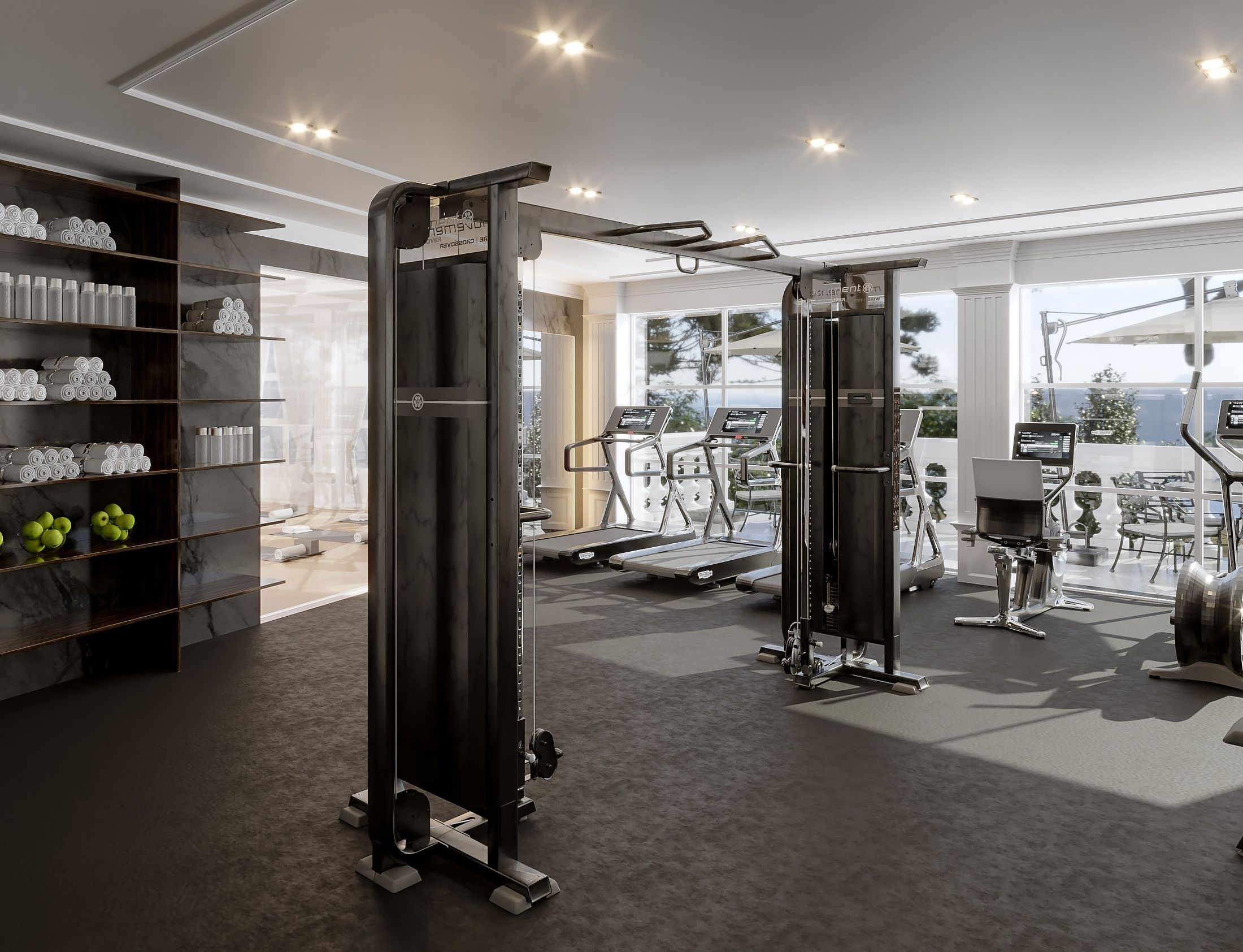 Ein Fitnessraum mit Trainingsgeräten, einer Rezeption und Blick ins Freie.