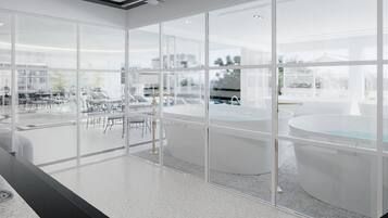 A modern interior with large windows, a pool area, and a seating area with tables and chairs.