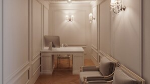 Una habitació amb un sòl de fusta en disseny de guió, un escriptori blanc amb una cadira, un sofà i aplics de paret.