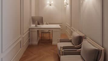 Een kamer met een houten visgraatvloer, een wit bureau met stoel, een bank en wandlampen.