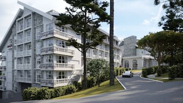 A multi-story hotel with balconies, a stone facade, and a parking area.