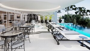 Un área interior de piscina moderna con sillones reclinables, una bañera de hidromasaje y una zona de estar con mesas y sillas.