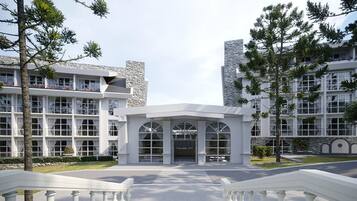 A modern hotel with a central entrance, multiple floors, and a stone facade.