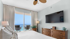 A hotel room with a large bed, a TV, a dresser, and a balcony with a view of the ocean. - Beachfront Bliss, Majestic Sun A1002 | Stunning Gulf Views & Resort Amenities (Miramar Beach)